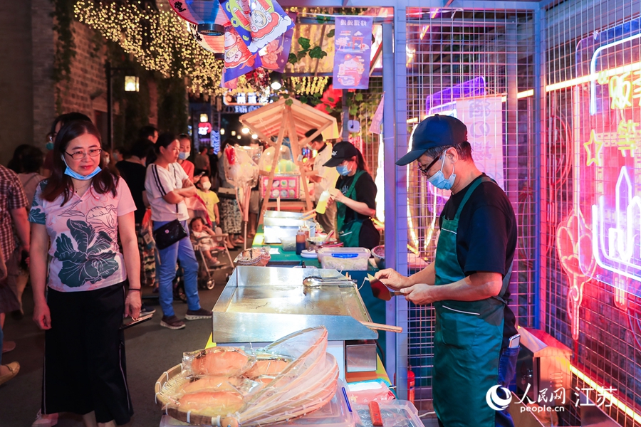 夜市老板正在準(zhǔn)備餐食。熙熙攝