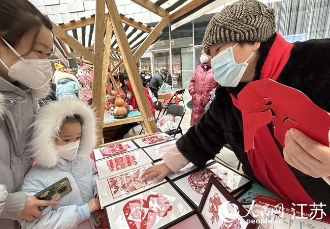 錢紀(jì)芳（右一）為市民介紹剪紙作品。人民網(wǎng) 顧姝姝攝